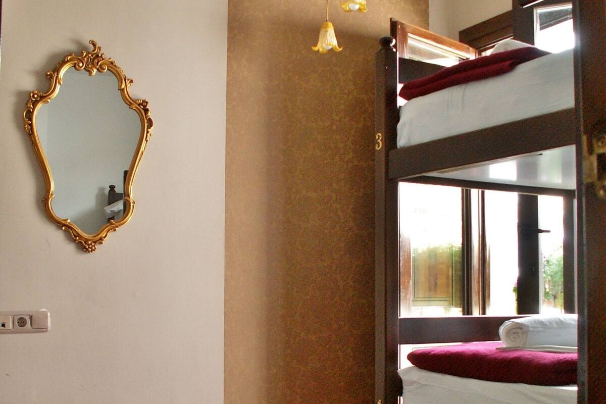 Una habitación con literas, un espejo y una lámpara colgante.