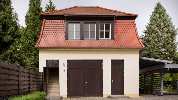 A two-story house with a red-tiled roof, a covered porch, and a paved driveway. - Ferienwohnung Fricke (Dresden)