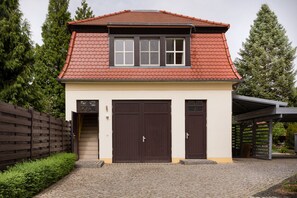 A two-story house with a red-tiled roof, a covered porch, and a paved driveway. - Ferienwohnung Fricke (Dresden)