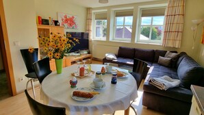 A dining area with a table set for two, a sofa, and a television. - Ferienwohnung Fricke (Dresden)