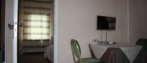 A hotel room with a bed, a television, and a dining table with chairs.