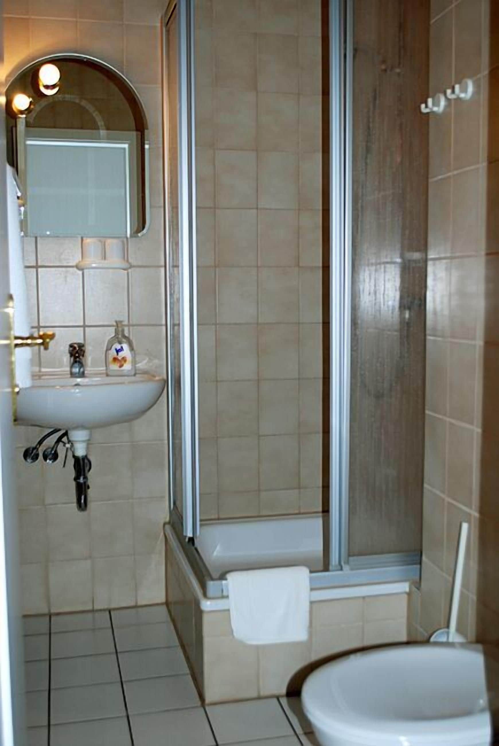 Uma casa de banho com chuveiro, lavatório e sanita.