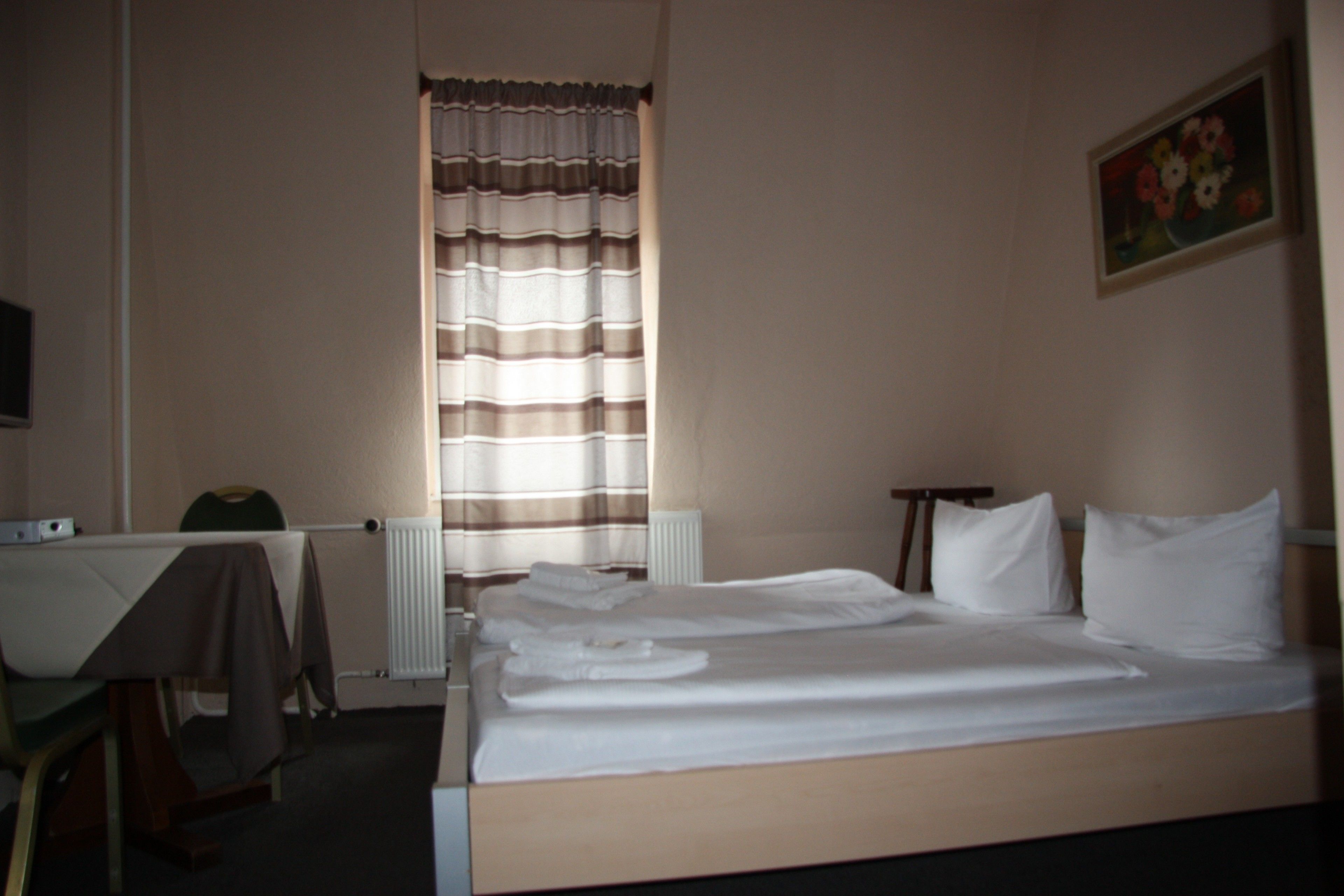 Ein Hotelzimmer mit Bett, Schreibtisch, Stuhl und Heizkörper.