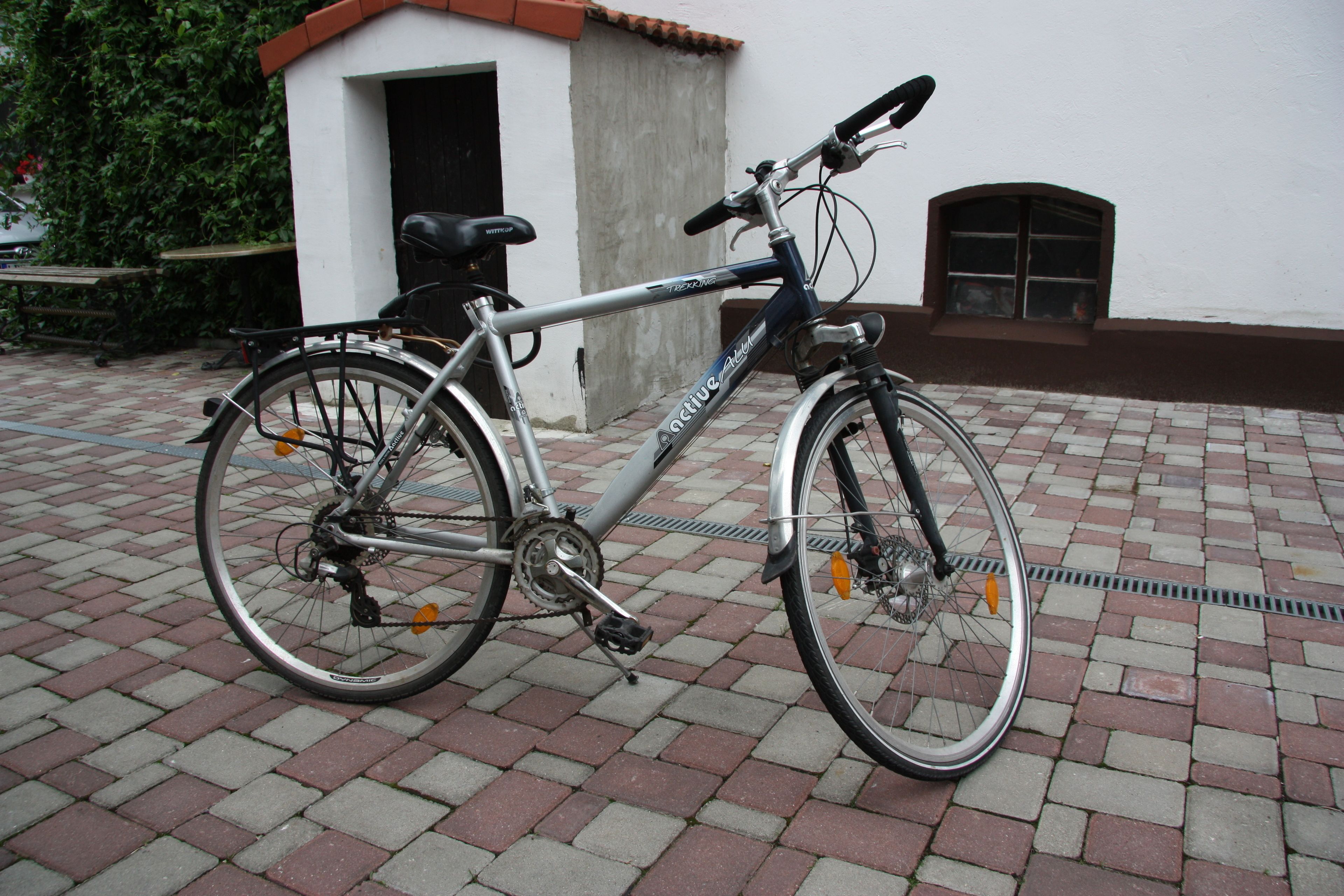 A stationary bicycle parked on a brick pavement.