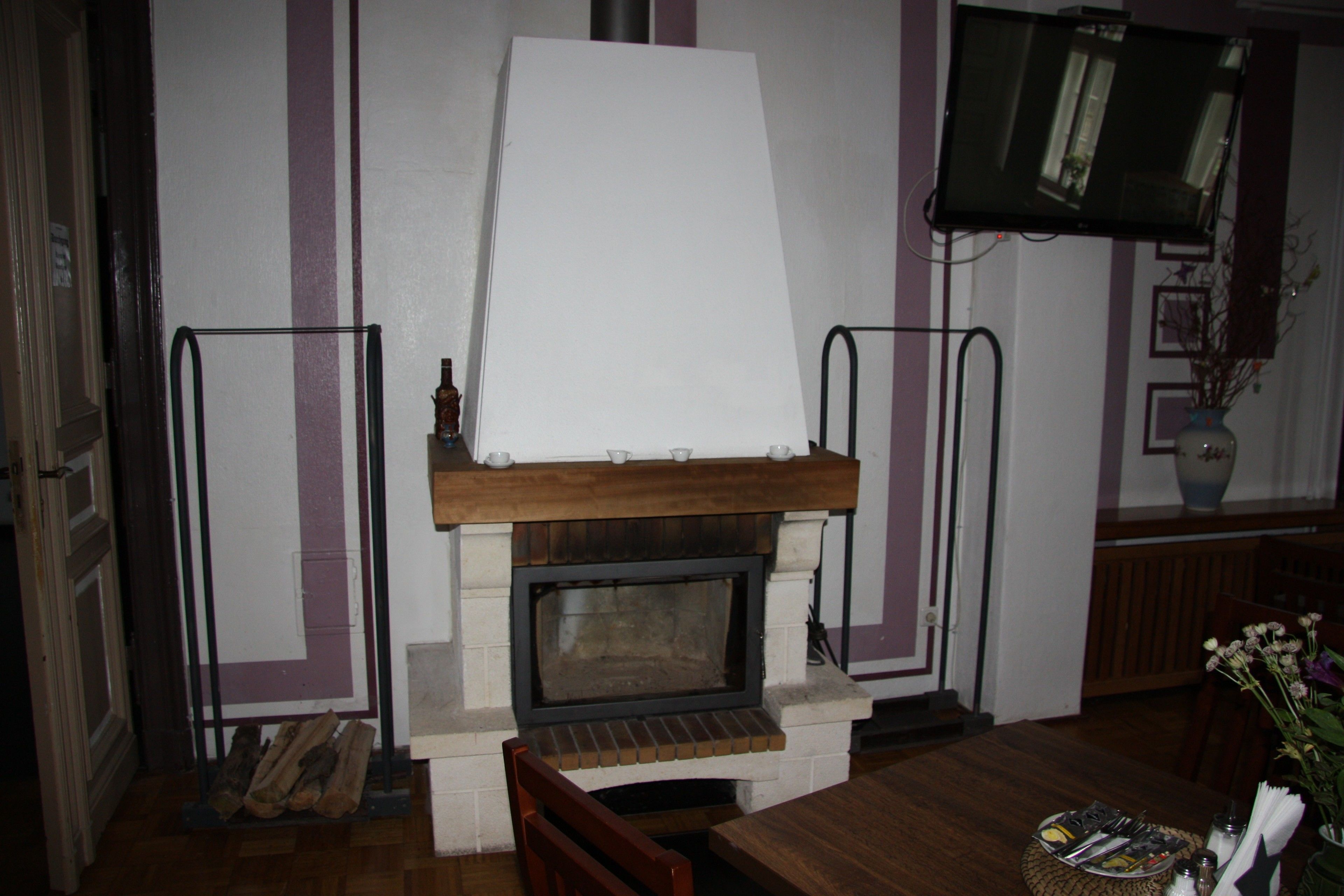 A room with a fireplace, a television mounted on the wall, and a dining table with chairs.