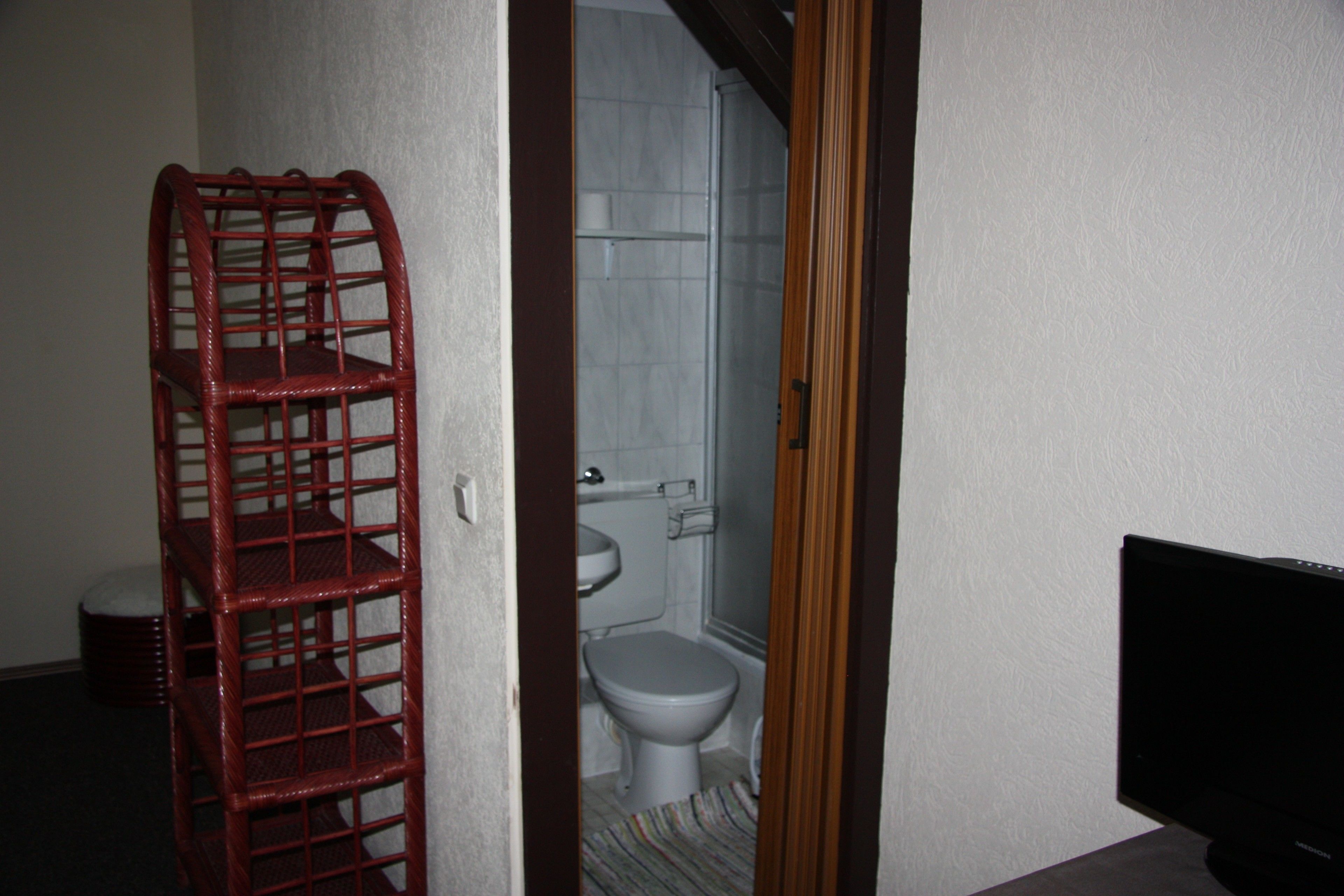 Un baño con inodoro, lavamanos y una silla roja.