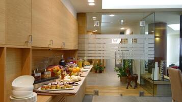 Une chambre d’hôtel moderne avec un comptoir de buffet en bois, une cloison en verre et une vue sur le paysage urbain.