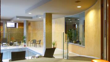 Eine moderne Lobby mit Poolbereich, Sitzgelegenheiten und einer Glastrennwand.