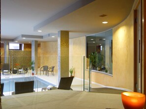 A modern lobby with a pool area, seating, and a glass partition. - Hotel Natura (Castel di Sangro)