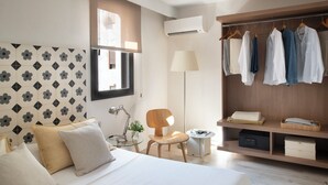 Moderni hotellihuone, jossa on sänky, työpöytä, tuoli, vaatekaappi ja ikkuna.