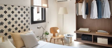 A modern hotel room with a bed, a desk, a chair, a wardrobe, and a window.