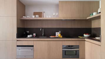 A modern kitchen with wooden cabinets, a stainless steel sink, and built-in appliances including a dishwasher and oven.
