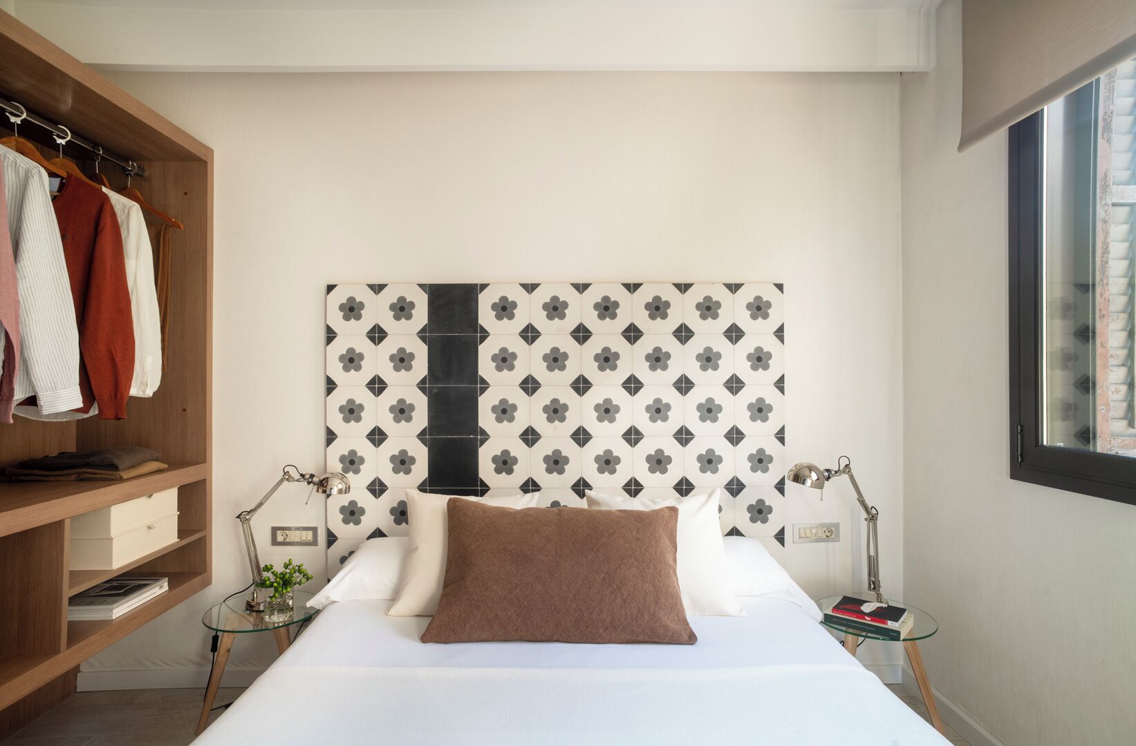 A bedroom with a bed, bedside tables, a wardrobe, and a patterned headboard.