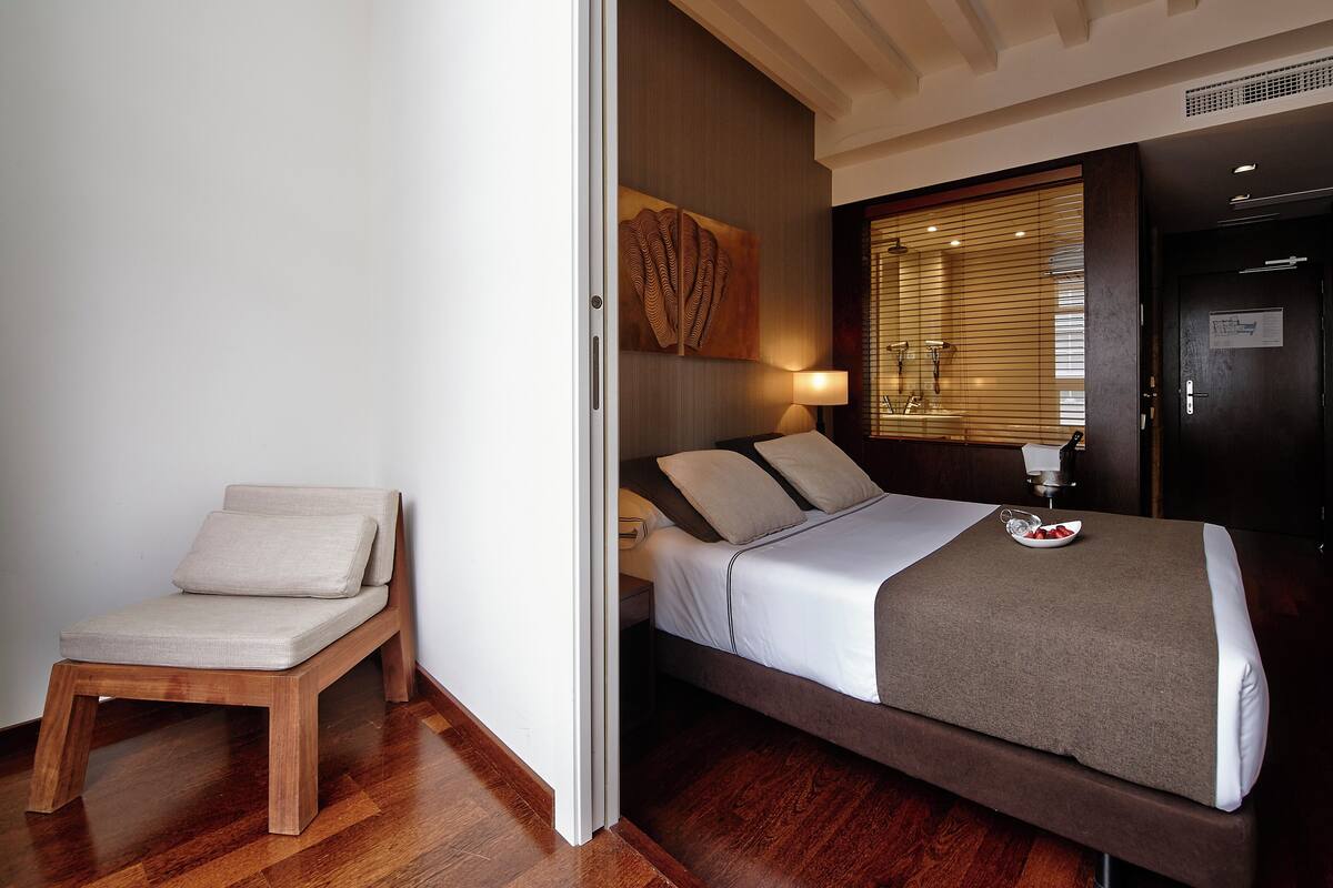 A neatly arranged bedroom with a bed, bedside table, and a chair.