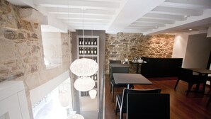 A modern dining area with stone walls, wooden flooring, and hanging pendant lights.