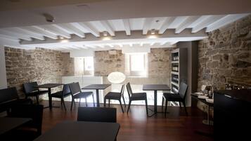 A modern dining area with stone walls, wooden tables and chairs, and a central light fixture.