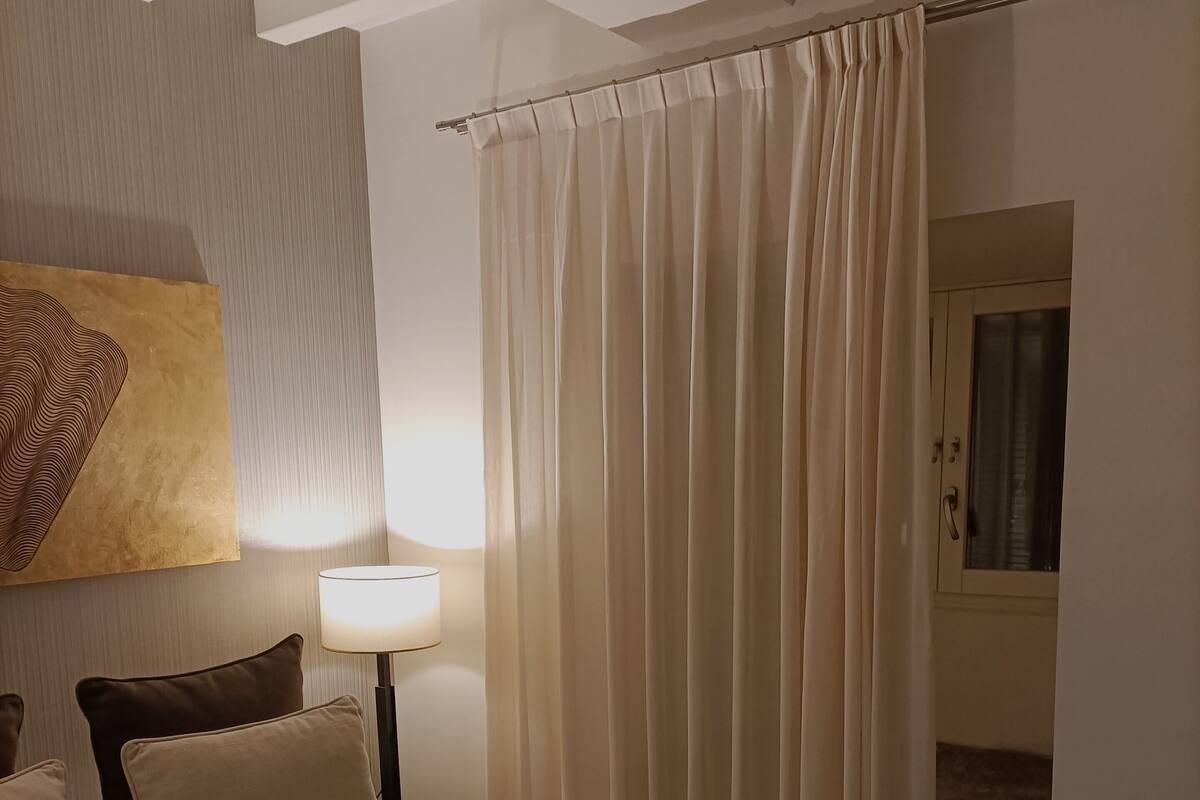 A hotel room with a large bed, a bedside lamp, a painting on the wall, and a curtain.