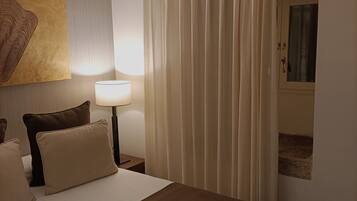 A hotel room with a large bed, a bedside lamp, a painting on the wall, and a curtain.