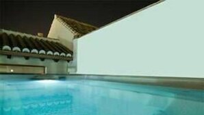A swimming pool with a tiled roof and a white wall in the background. - Hotel Palacio Blanco (Velez-Malaga)