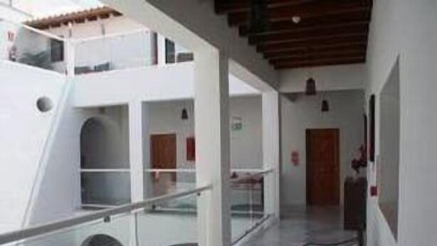 A corridor with a glass railing, white walls, and a wooden ceiling. There are doors and windows along the corridor. - Hotel Palacio Blanco (Velez-Malaga)