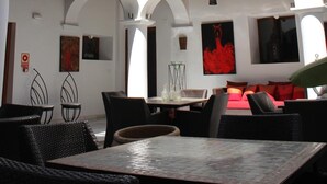 A multi-level outdoor seating area with tables and chairs, a balcony, and a dining area with a red sofa. - Hotel Palacio Blanco (Velez-Malaga)