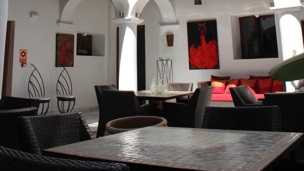 A multi-level outdoor seating area with tables and chairs, a balcony, and a dining area with a red sofa. - Hotel Palacio Blanco (Velez-Malaga)