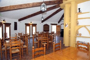 A dining hall with wooden tables and chairs, a high ceiling with exposed beams, and hanging lantern-style lights. - Cuevas del Zenete (La Calahorra)