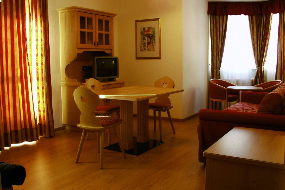 Una sala acogedora con una mesa de madera, dos sillas, un sofá y un televisor.