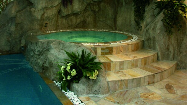 An indoor swimming pool with a hot tub, stone steps, and surrounding rock walls. - Residence Pez Gajard (Primiero San Martino di Castrozza)