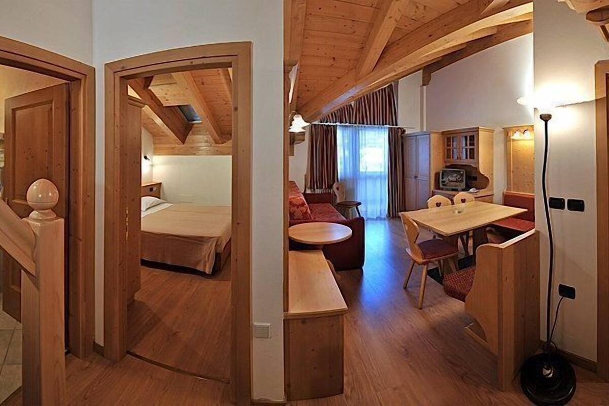 Una habitación acogedora con una cama, una mesita y un sofá. Hay un televisor y una lámpara.