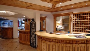 A spacious kitchen with wooden cabinetry, a curved island, and a wine rack. - Residence Pez Gajard (Primiero San Martino di Castrozza)