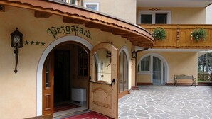 A building with a wooden facade, arched doorways, and a stone-tiled courtyard. - Residence Pez Gajard (Primiero San Martino di Castrozza)
