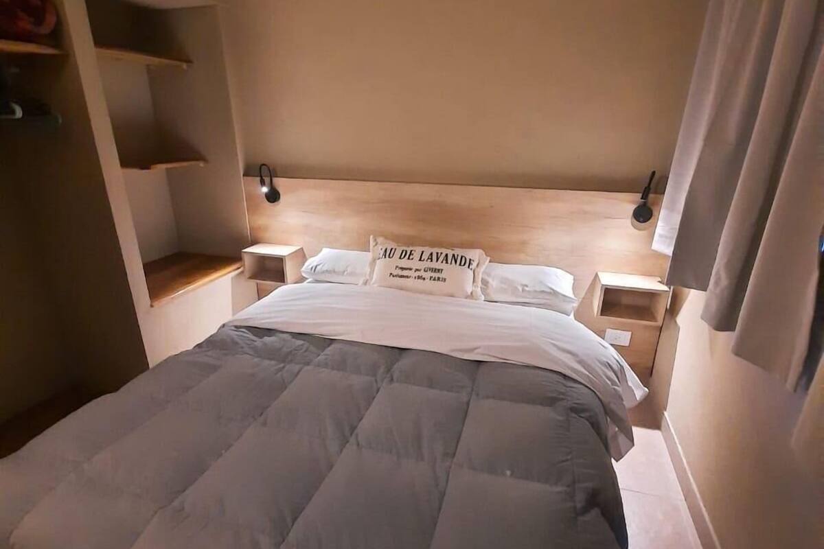 Une chambre à coucher avec un grand lit, une tête de lit en bois, des tables de chevet et une petite table de nuit.