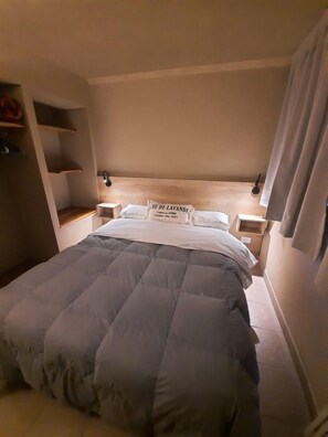 A bedroom with a large bed, wooden headboard, bedside tables, and a nightstand. - Le Bouquet Apart Hotel (Bariloche)