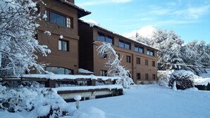 A multi-story building with a snow-covered exterior and surrounding trees.