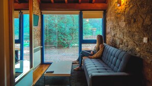 Una habitación acogedora con pared de piedra, vigas de madera en el techo y sofá azul.
