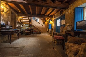A rustic interior with stone flooring, wooden beams, a staircase, and traditional furnishings. - Casa Perfeuto María (Outes)