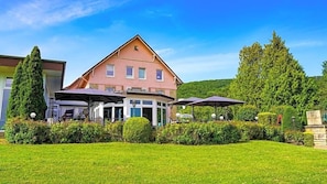 A two-story building with a garden in front, featuring a covered outdoor seating area with umbrellas. - Altes Zollhaus (Rinteln)