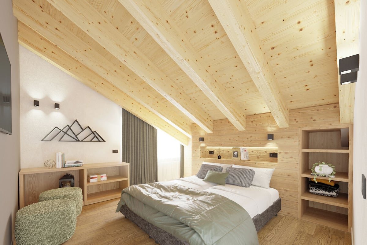 Un dormitorio moderno con techo de madera, una cama con almohadas, una mesita de noche, una estantería y un aplique de pared.