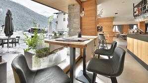 Une cuisine moderne avec un plafond en bois, un mur en pierre et une vue sur une montagne enneigée.