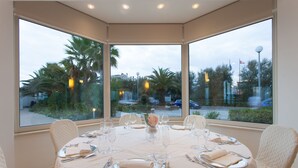 Mesa de comedor para seis personas, con vista a palmeras y un estacionamiento a través de amplias ventanas.