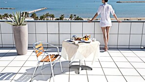 Un balcón con una mesa preparada para el desayuno, una planta en maceta y una silla.