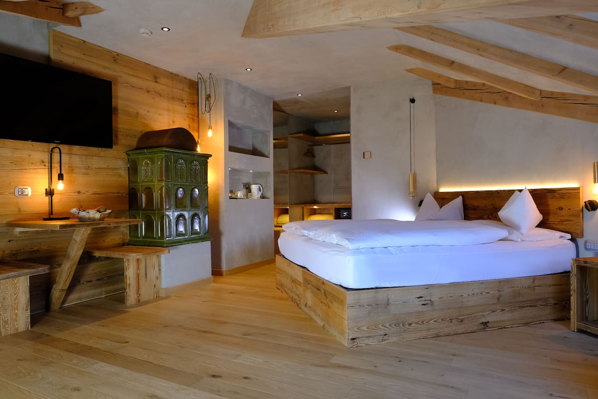 A wooden bedroom with a bed, a TV, and a green cabinet.