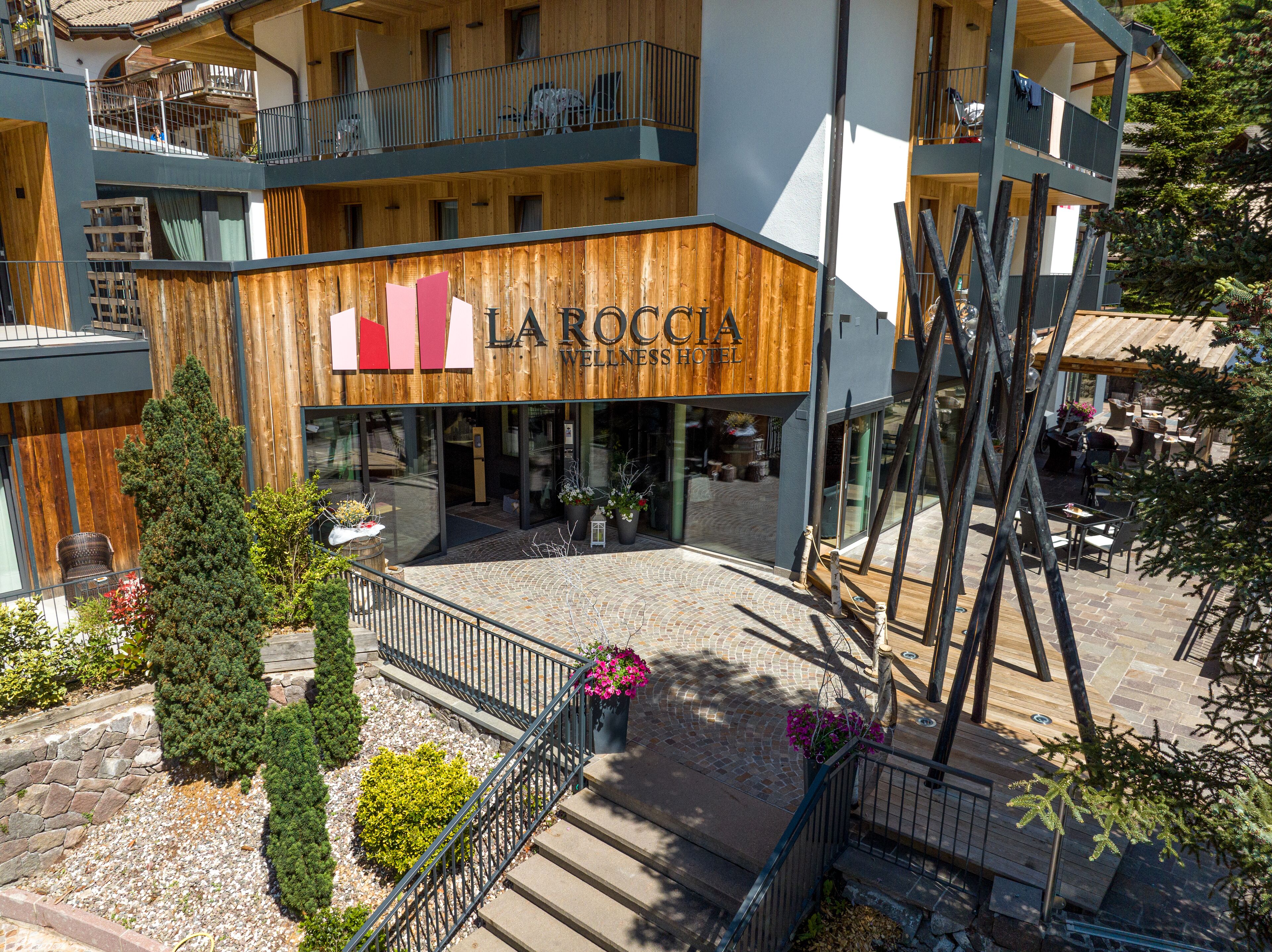 Een hotel met een houten gevel, een balkon en terrasplaatsen.