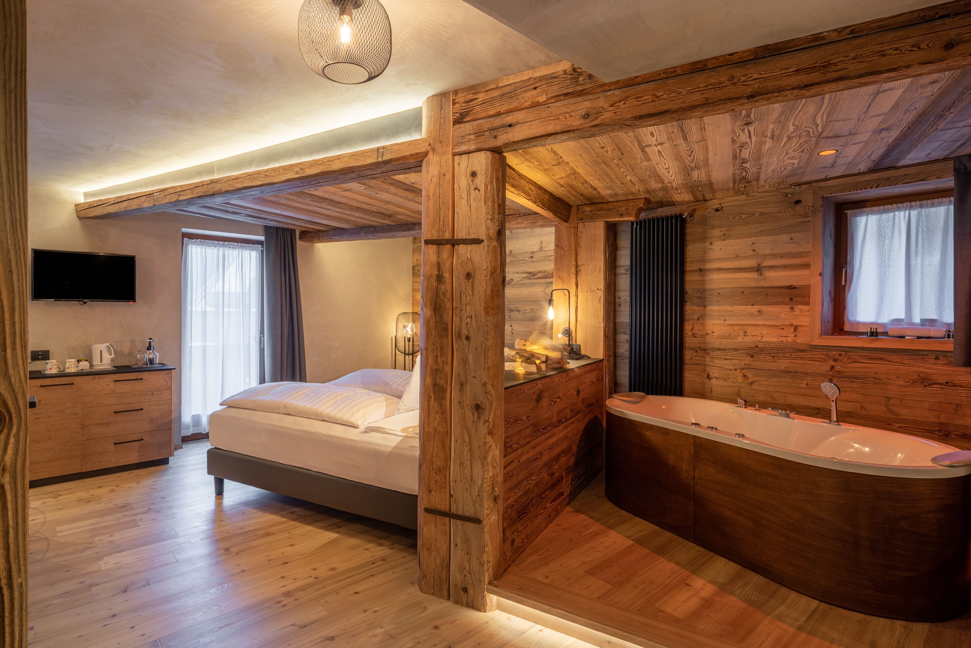 Un dormitorio moderno con techo de madera, una cama grande, una bañera integrada y un televisor de pantalla plana.