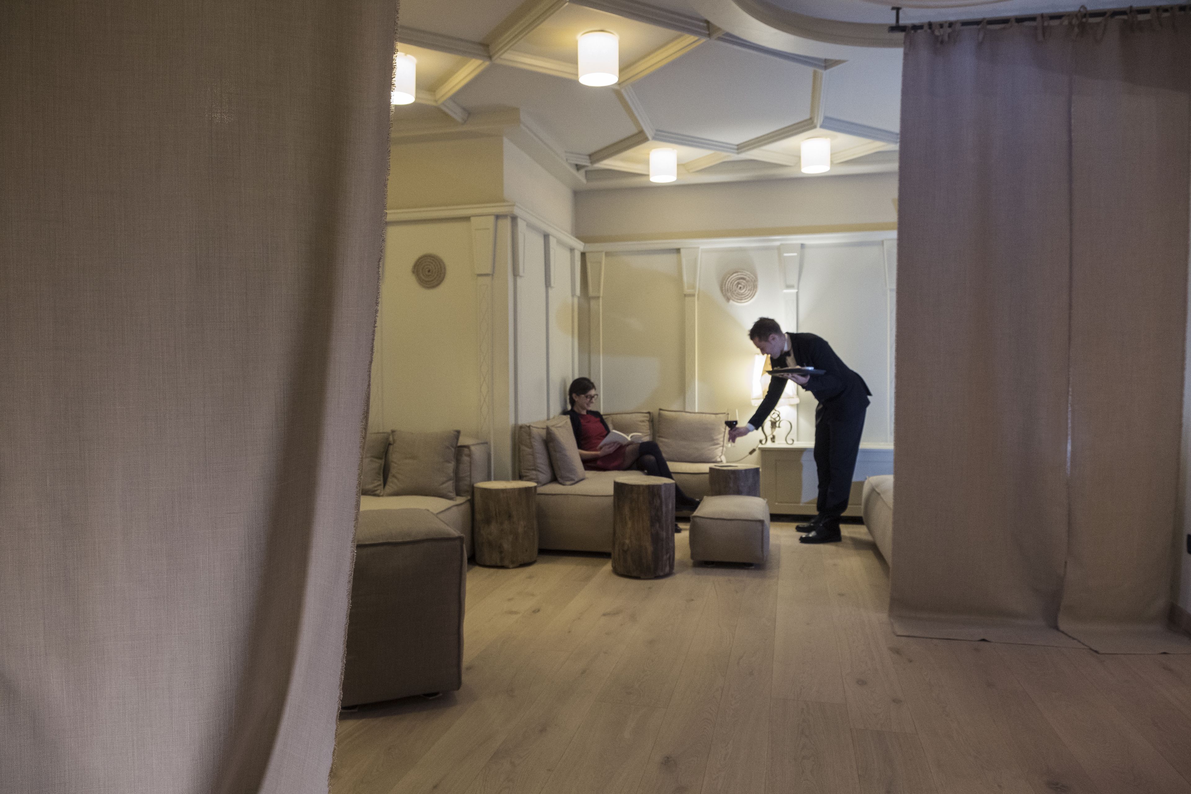 A modern living room with a sofa, ottoman, and wooden side tables.