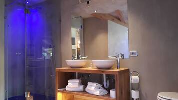 Une salle de bain moderne avec une douche à parois de verre, un meuble-lavabo en bois doté de deux vasques et des toilettes.