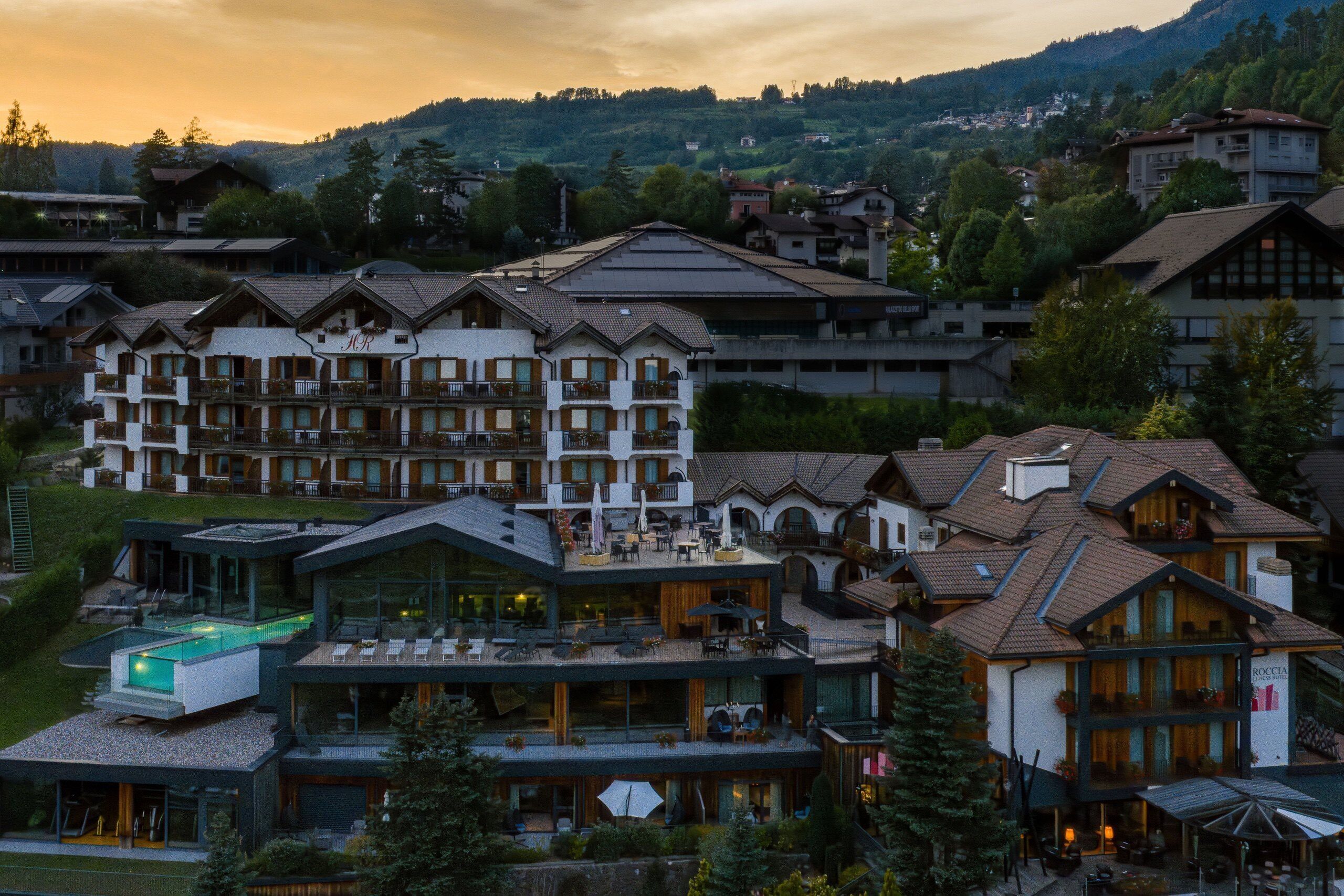 A modern hotel with multiple floors, outdoor seating areas, and a swimming pool.