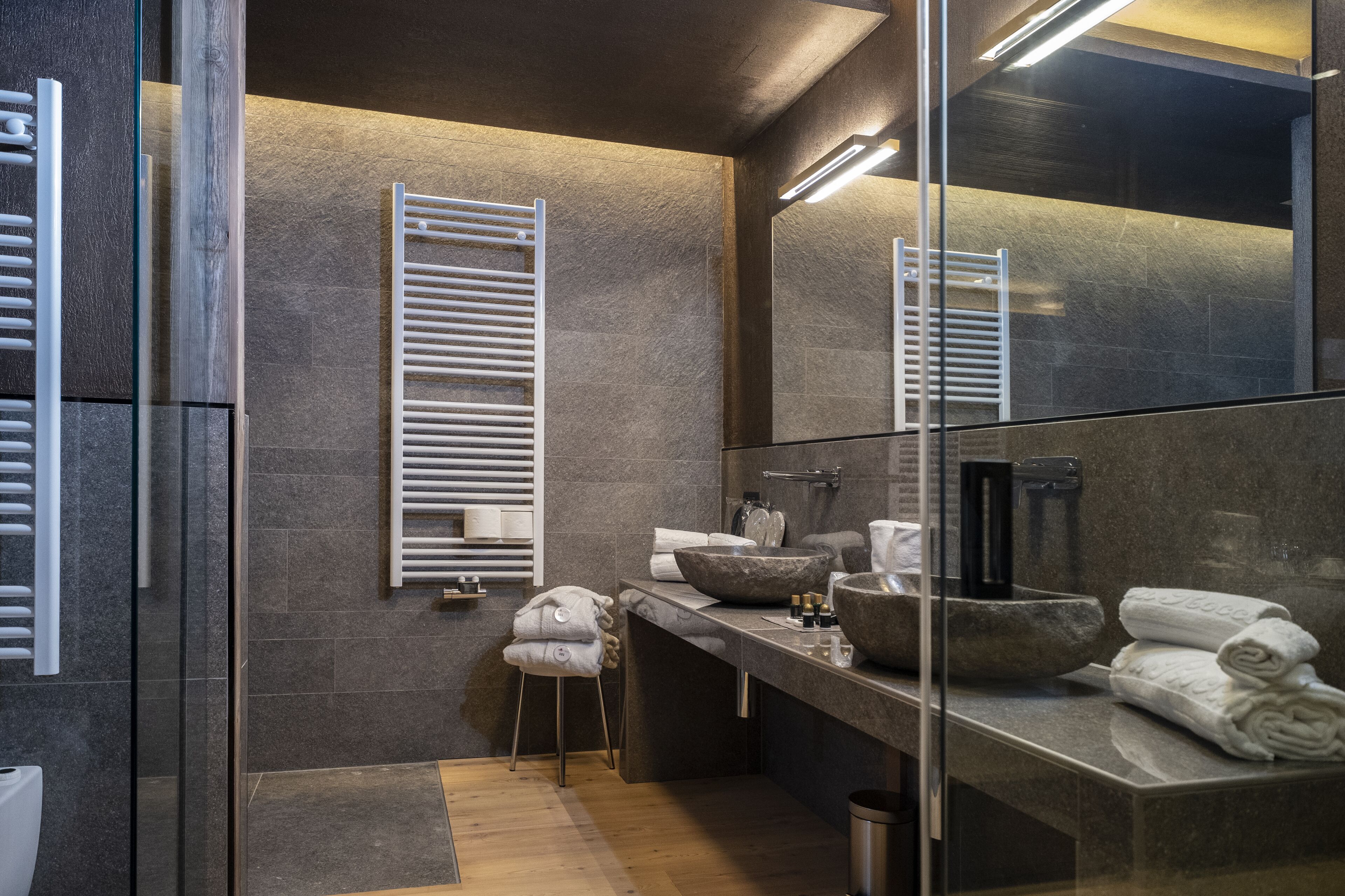 Un bagno moderno con un ampio specchio, un lavabo in pietra e un porta asciugamani.