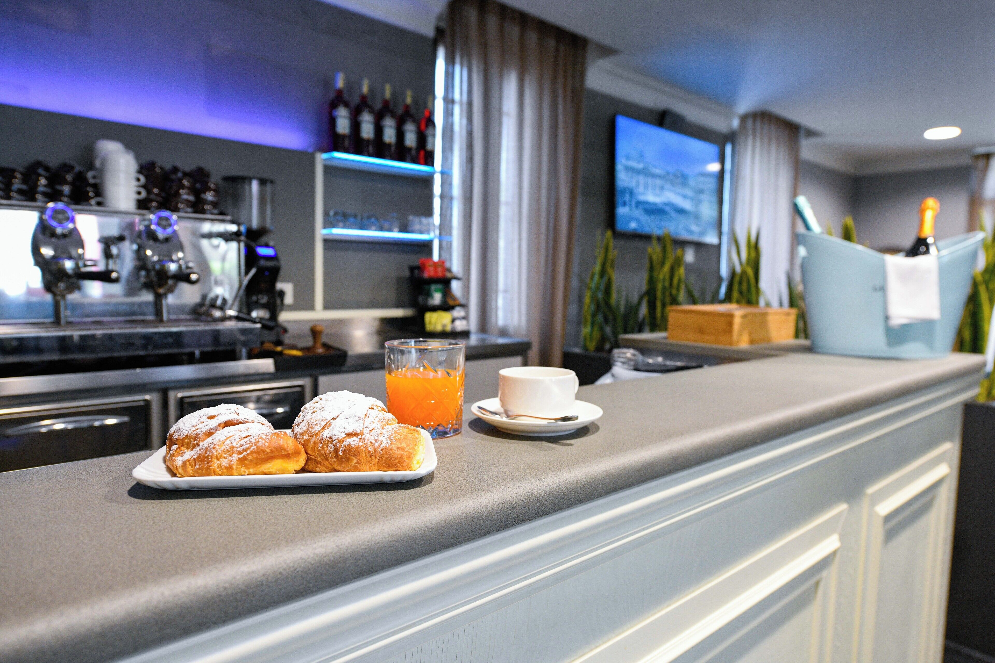 Un coin bar avec des pâtisseries, un verre de jus d’orange et une tasse de café.